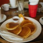 Delicious homemade pancakes served with syrup, whipped cream, and coffee on a breakfast table