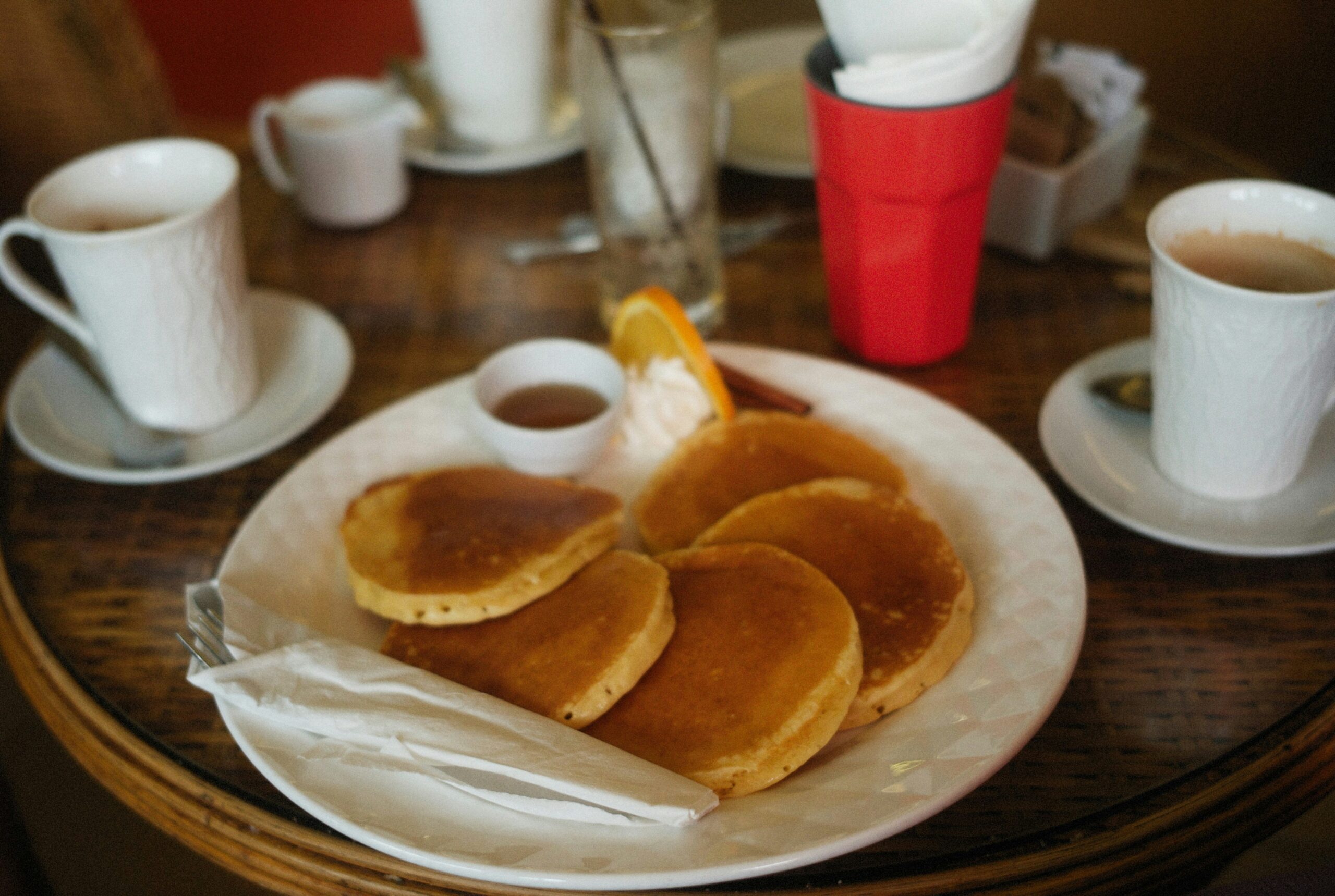 Delicious homemade pancakes served with syrup, whipped cream, and coffee on a breakfast table