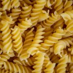"A close-up, top-down view of a pile of dry fusilli pasta."