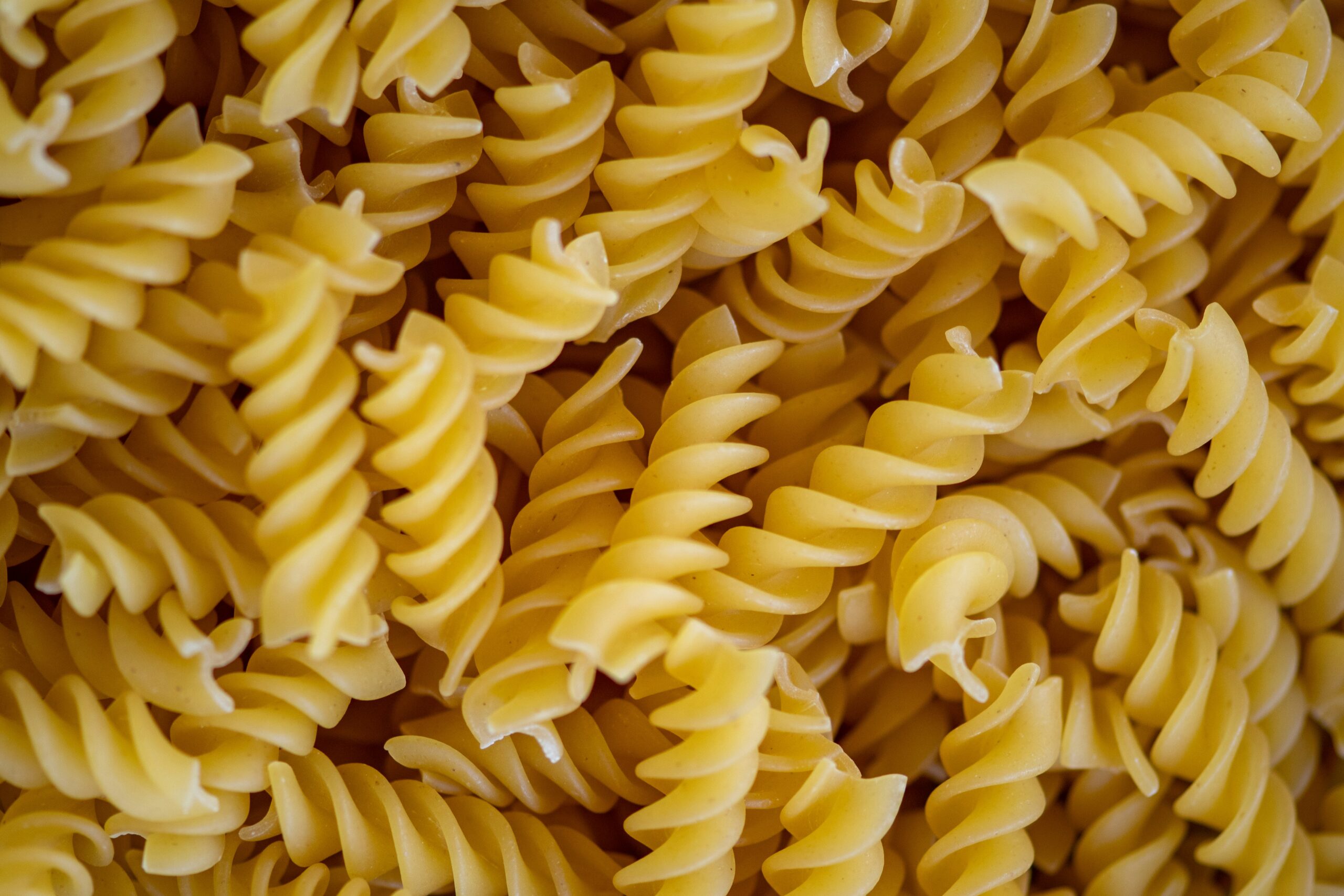 "A close-up, top-down view of a pile of dry fusilli pasta."