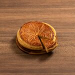 Crispy pie crust with intricate pattern and flaky texture sliced on wooden surface