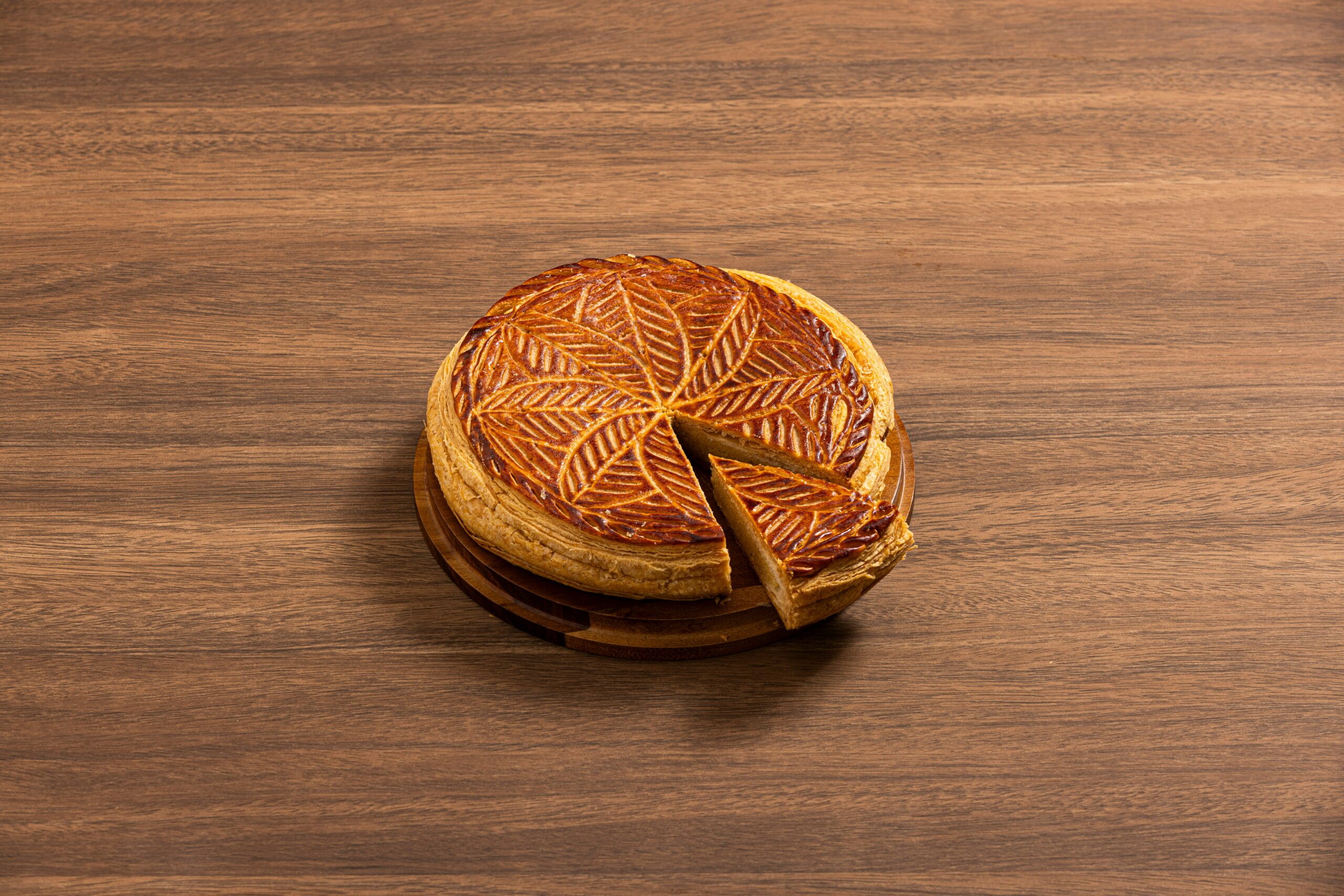 Crispy pie crust with intricate pattern and flaky texture sliced on wooden surface
